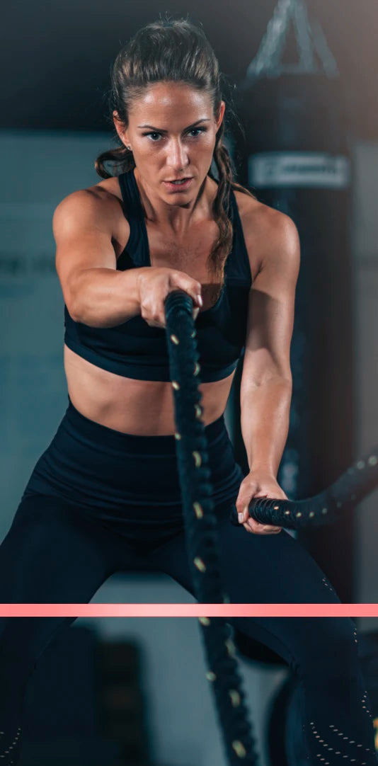 Woman performing battle rope workout representing strength, endurance, and active lifestyle supported by Premier Line supplements
